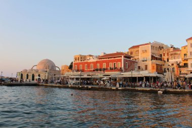 CHANIA, CRETE ADA, GREECE - 28 Temmuz 2016: Kucuk Hasan Paşa Camii ve turistlerle dolu eski Venedik limanı manzarası ve gün batımında Akti Tompazi Caddesi 'ndeki güzel tarihi binalar.