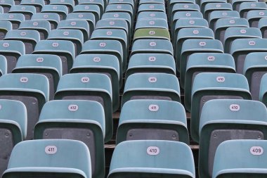 Açık hava amfitiyatrosunda numaralandırılmış boş plastik koltuklar..