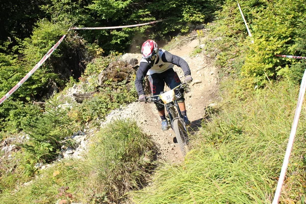 INNSBRUCK, AUSTRIA - 29 Ağustos 2015: Nordkette Alp dağ zincirinde Nordkette Downhill Pro yarışması sırasında tam donanımlı profesyonel motorcu dağ bisikleti sürüyor.