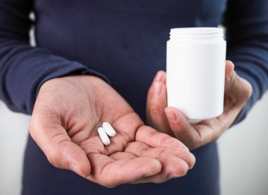 Sağlıksız genç bir kadın oturma odasında sağlığı için ilaç alıyor. Sağlık ve tıbbi konsept.