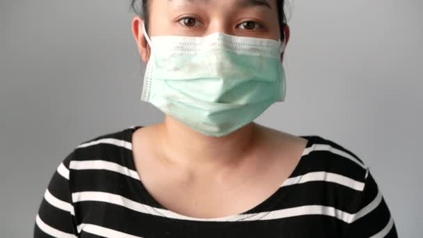 亚洲年轻女子戴着面部面具 以防止空气污染或灰色背景的病毒传播 空气污染 灰尘过敏和保健的概念 — 图库视频影像