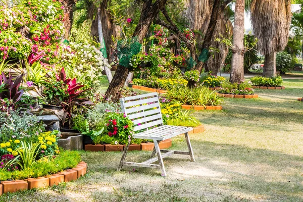 Cadeira branca no jardim de flores acolhedor . — Fotografia de Stock