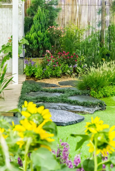 Stone pathway in cozy garden./ Stone pathway, flowerpot, plant, grass decoration in cozy garden on summer.