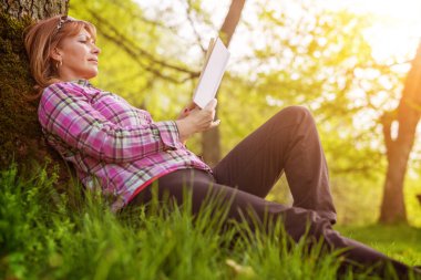 Parkta kitap okuyan kadın.