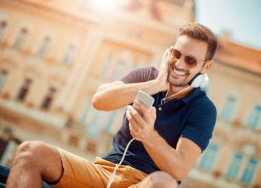 Genç adam bir akıllı telefon üzerinde müzik dinleme