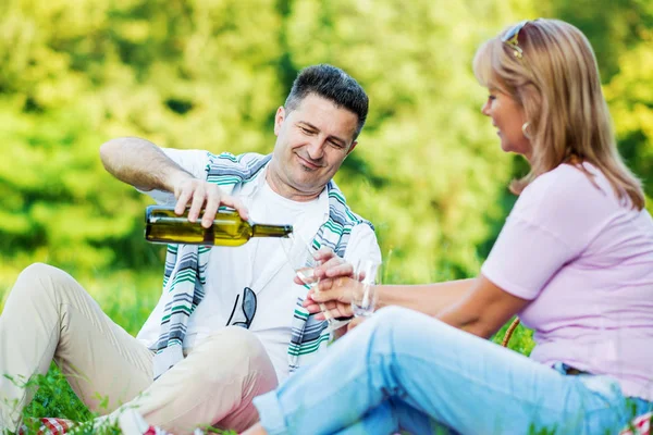 Casal desfrutando de vinho branco no piquenique — Fotografia de Stock