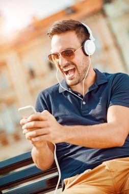 Genç adam bir akıllı telefon üzerinde müzik dinleme