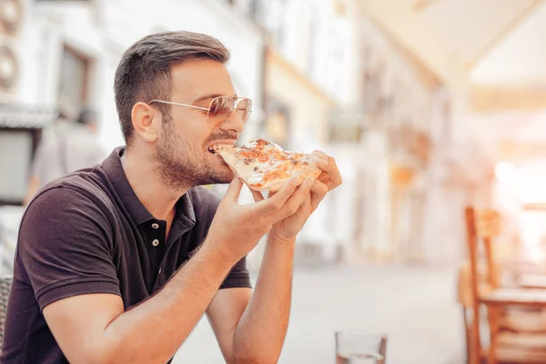 Joven comiendo una rebanada de pizza — Foto de Stock