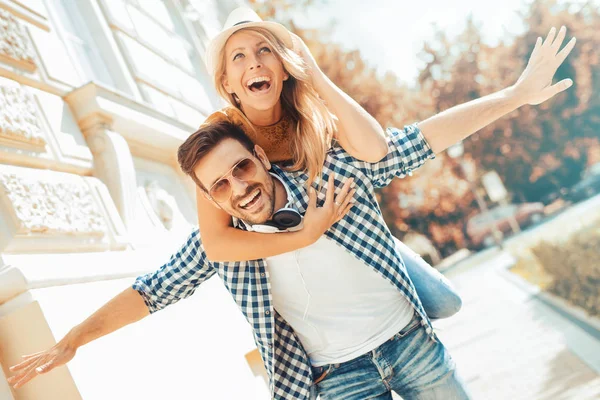 Joven hombre dando a su novia un piggyback — Foto de Stock