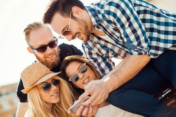 Nära upp skott av vänner tittar på smart telefon — Stockfoto