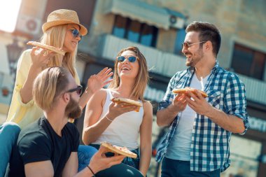 Dört genç neşeli insanlar pizza yemek Close-Up