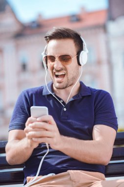 Kulaklıklar giyen genç çekici adam gülümsüyor