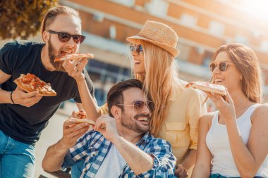Kendi dilim pizza alarak arkadaş grubu