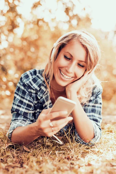 Mujer atractiva joven está sonriendo mientras usa auriculares — Foto de Stock