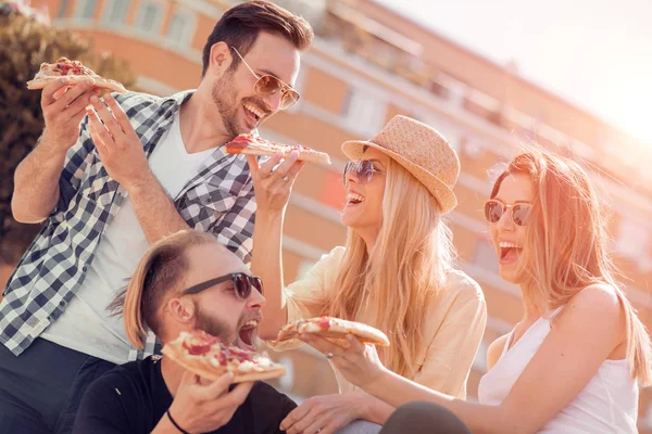 ピザのスライスをとる友人のグループ — ストック写真