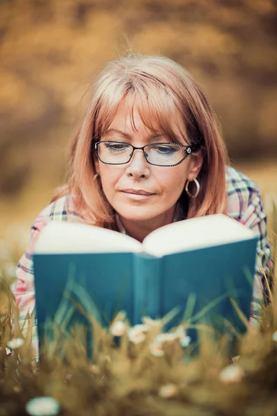 Nő olvasókönyv a parkban a fűben — Stock Fotó