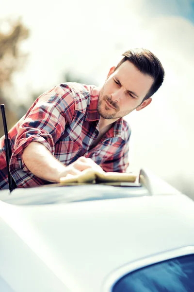 Молодой человек чистит свою машину на улице — стоковое фото