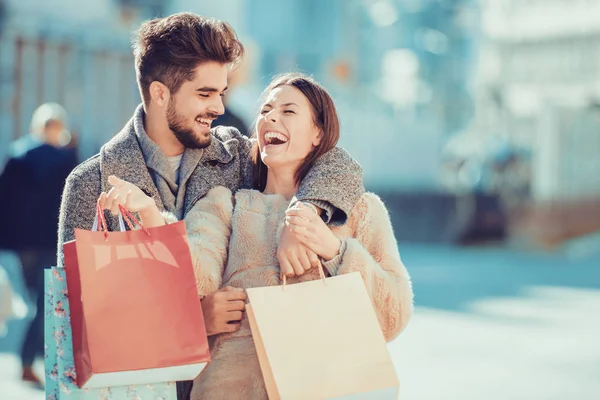 Hermosa pareja amorosa joven llevando bolsas de compras —  Fotos de Stock