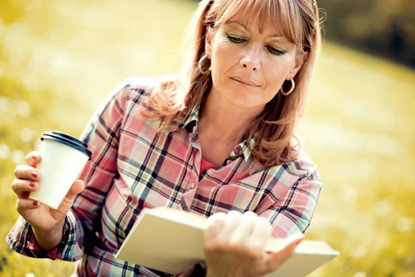 Parkta kitap okuyan kadın.