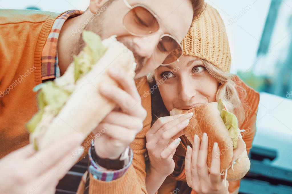 Couple eating sandwich outdoor