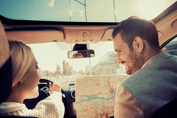 Smiling man and woman using map on roadtrip