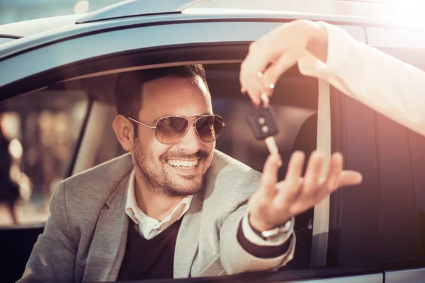 Mladý muž obdrží klíč od auta od prodavačka — Stock fotografie