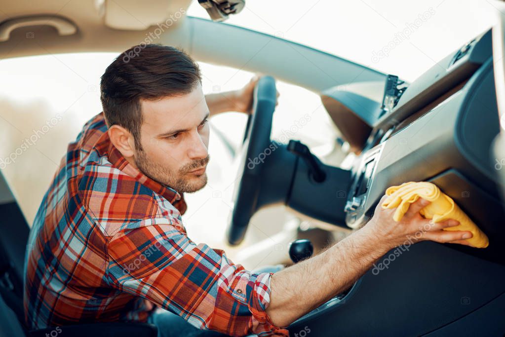 Young man cleaning car interior