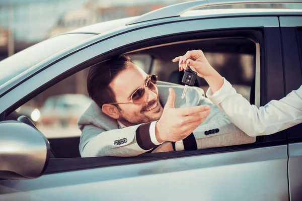 Νεαρός άνδρας λαμβάνει το κλειδί του αυτοκινήτου από την πωλήτρια — Φωτογραφία Αρχείου