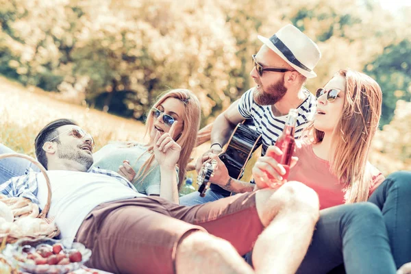 Счастливые юные друзья устраивают пикник в парке — стоковое фото