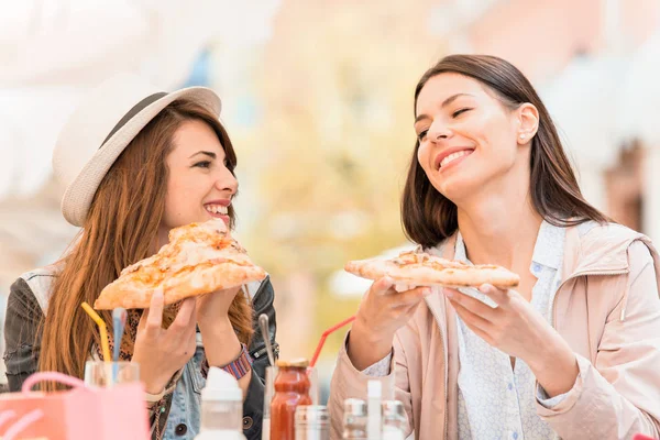 Girls eating pizza in a outdoor cafe