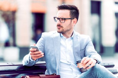 İş adamı açık havada akıllı telefon kullanıyor.