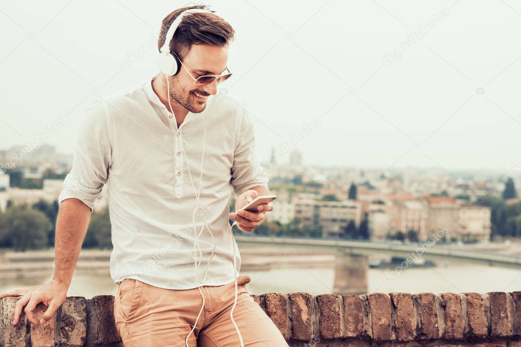 Young attractive man is smiling while wearing headphones