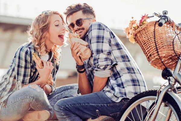 Pareja joven comiendo sándwich al aire libre — Foto de Stock