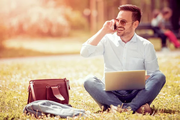 Jovem usando laptop no parque — Fotografia de Stock