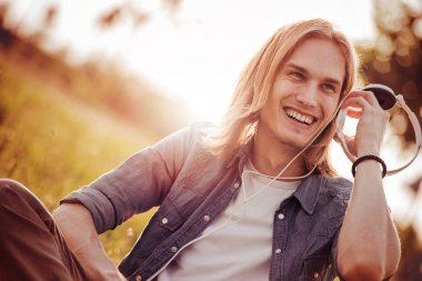 çimenlerin üzerinde oturan ve müzik dinlemek adam