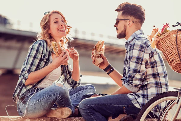 Пара смеется и ест сэндвичи — стоковое фото