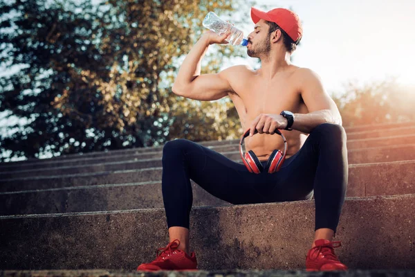Чоловік п'є воду після тренування — стокове фото