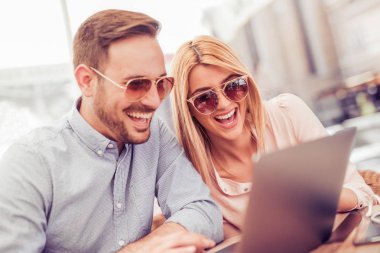 Laptop kullanan neşeli bir çift.