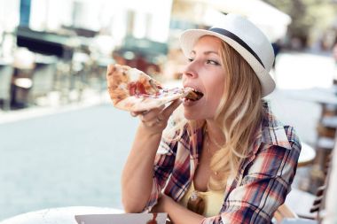 Genç kadın bir dilim pizza kafede yemek