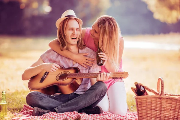 Man met zijn meisje gitaarspelen op een picknick — Stockfoto