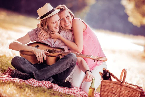 Mężczyzna gra na gitarze do jego dziewczyna na piknik — Zdjęcie stockowe