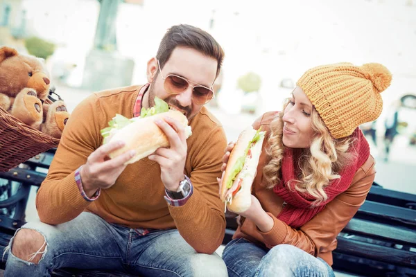Пара смеется и ест сэндвич — стоковое фото