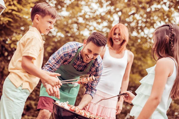Happy family having a barbecue in their garden in summer — Stock Photo, Image