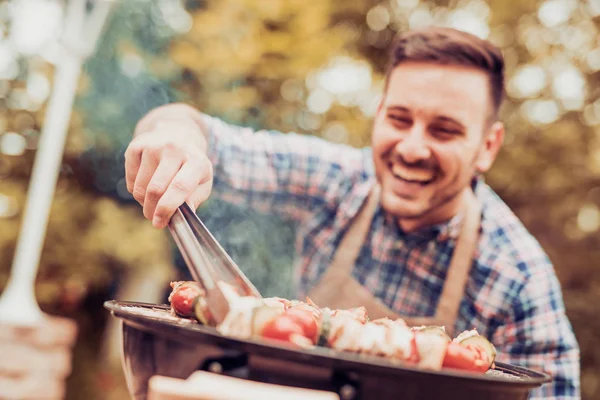 Young man cooking meat on barbecue — Stock Photo, Image