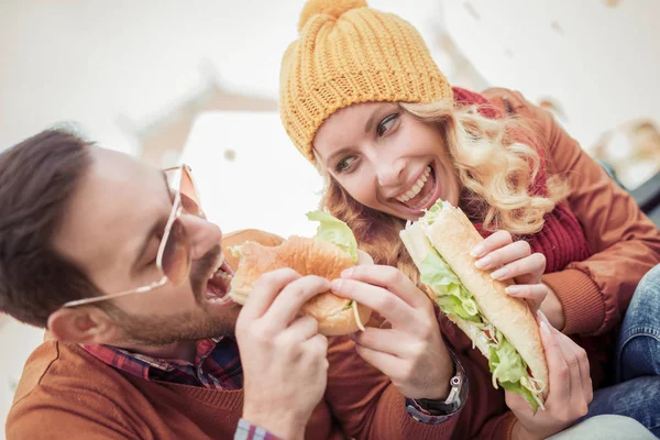 Belo jovem casal comer sanduíches — Fotografia de Stock