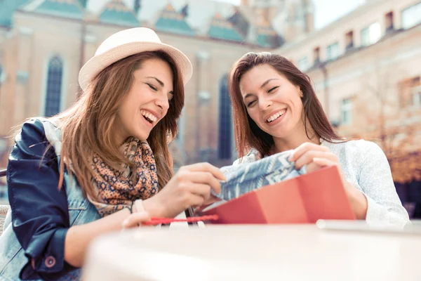 Feliz shopaholic mulheres verificando roupas no café . — Fotografia de Stock