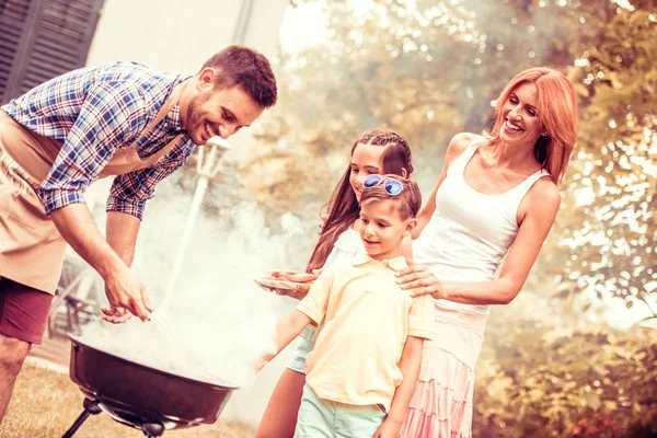 Família feliz fazendo um churrasco em seu jardim — Fotografia de Stock