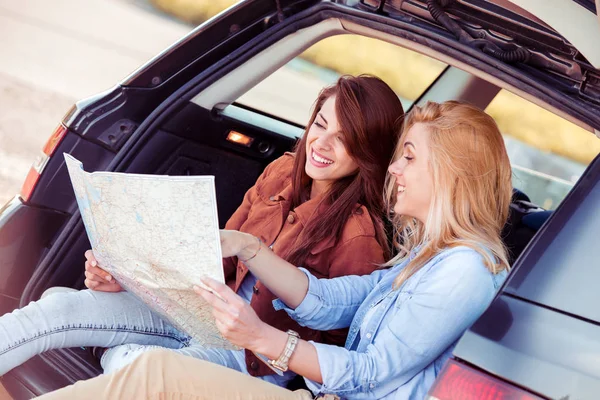 Zwei junge Frauen mit Auto schauen sich Straßenkarte an — Stockfoto