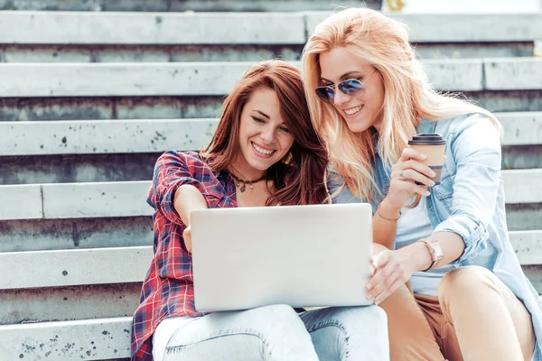 Dos mujeres jóvenes utilizando un ordenador portátil al aire libre . — Foto de Stock