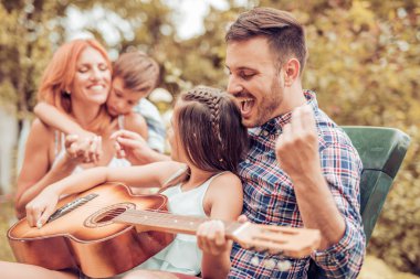 Birlikte gitar çalmak ve gülerek mutlu bir genç aile